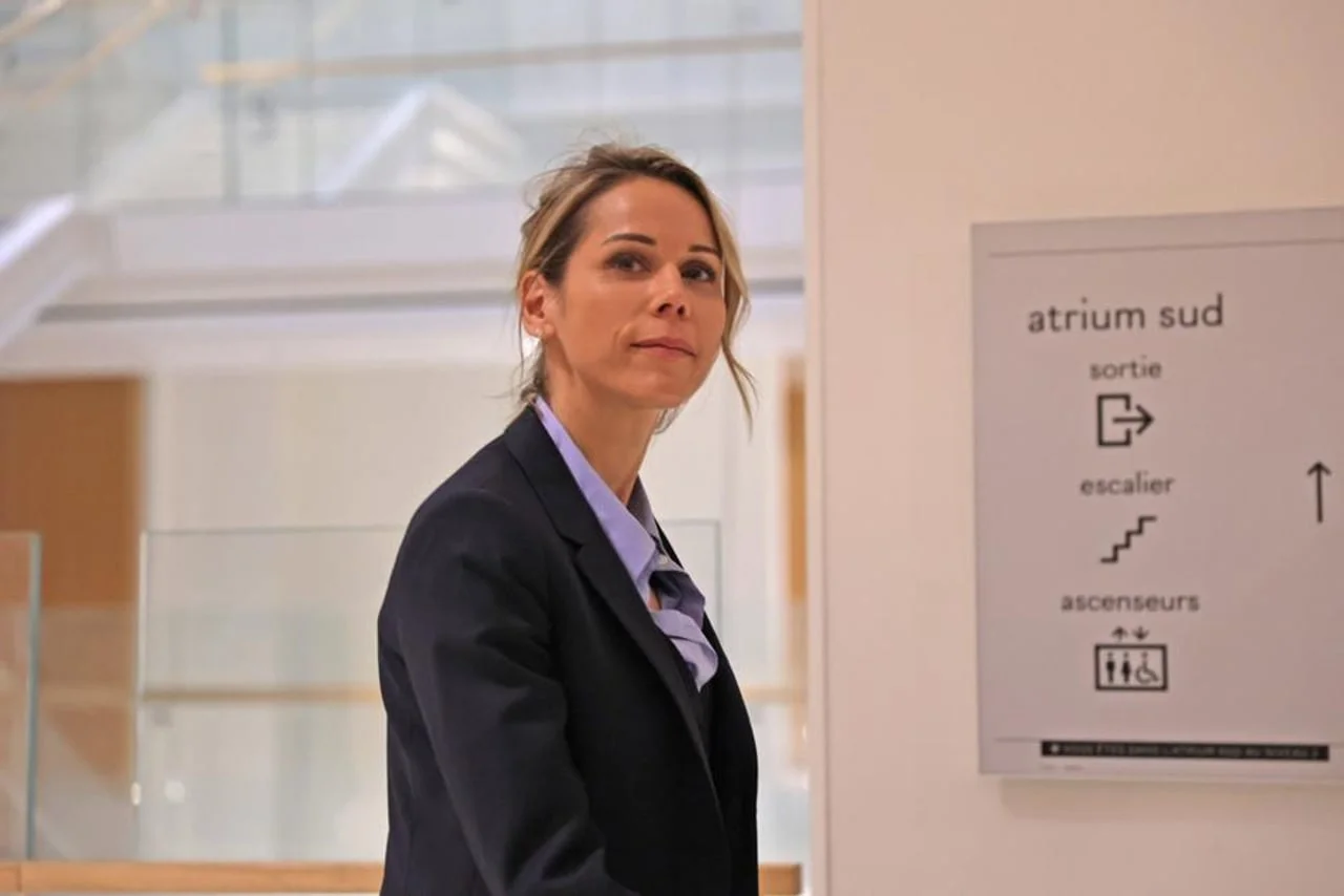 Žena u poslovnom odjevanju stoji pored putokaza Atrium Sud
