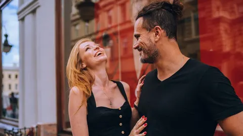 Nasmijani muškarac i žena koji se gledaju u oči na ulici