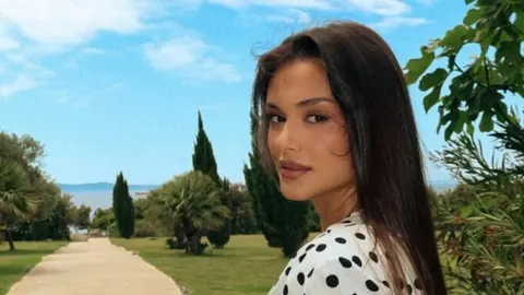 Portret Laure Gnjatović u bijeloj haljini s crnim točkicama na otvorenom