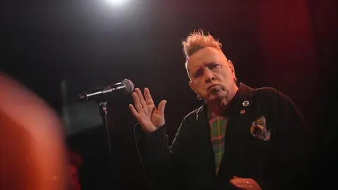 Punk glazbenik s karakterističnim frizurom stoji ispred mikrofona
