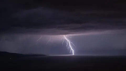 Snažan grom udara u more pod tamnim oblacima noću