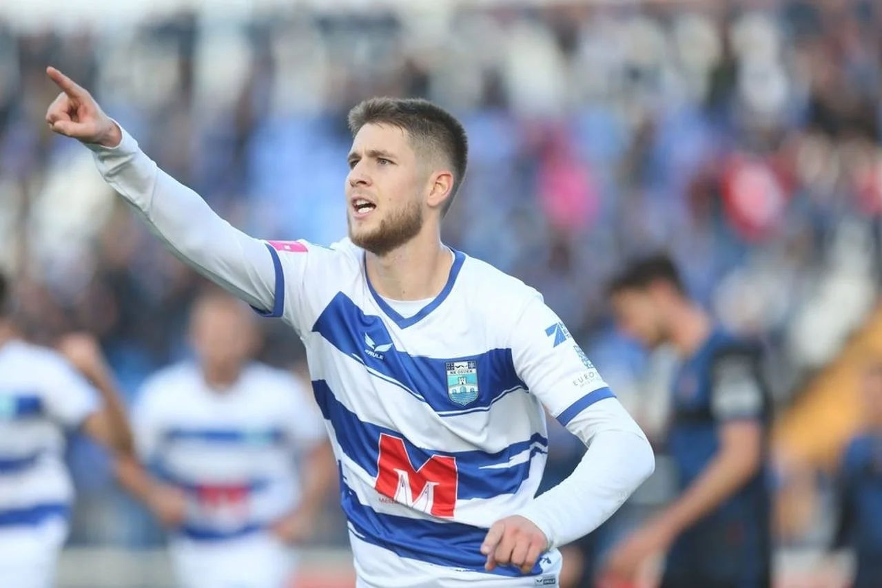 Nogometni igrač u plavo-bijelom dresu slavi gol na terenu