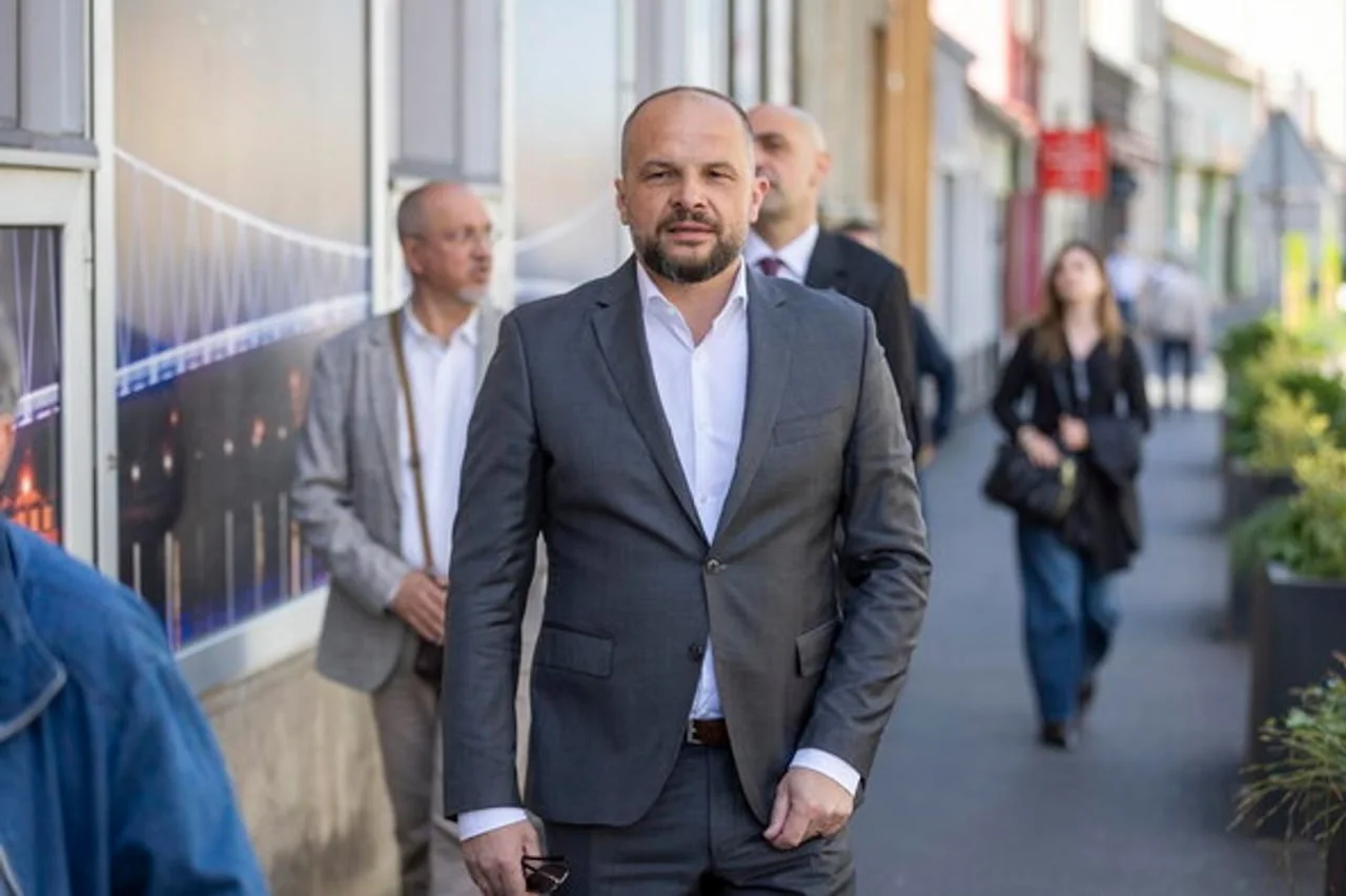 Siniša Hajdaš Dončić u sivom odelu hoda ulicom pored zgrada