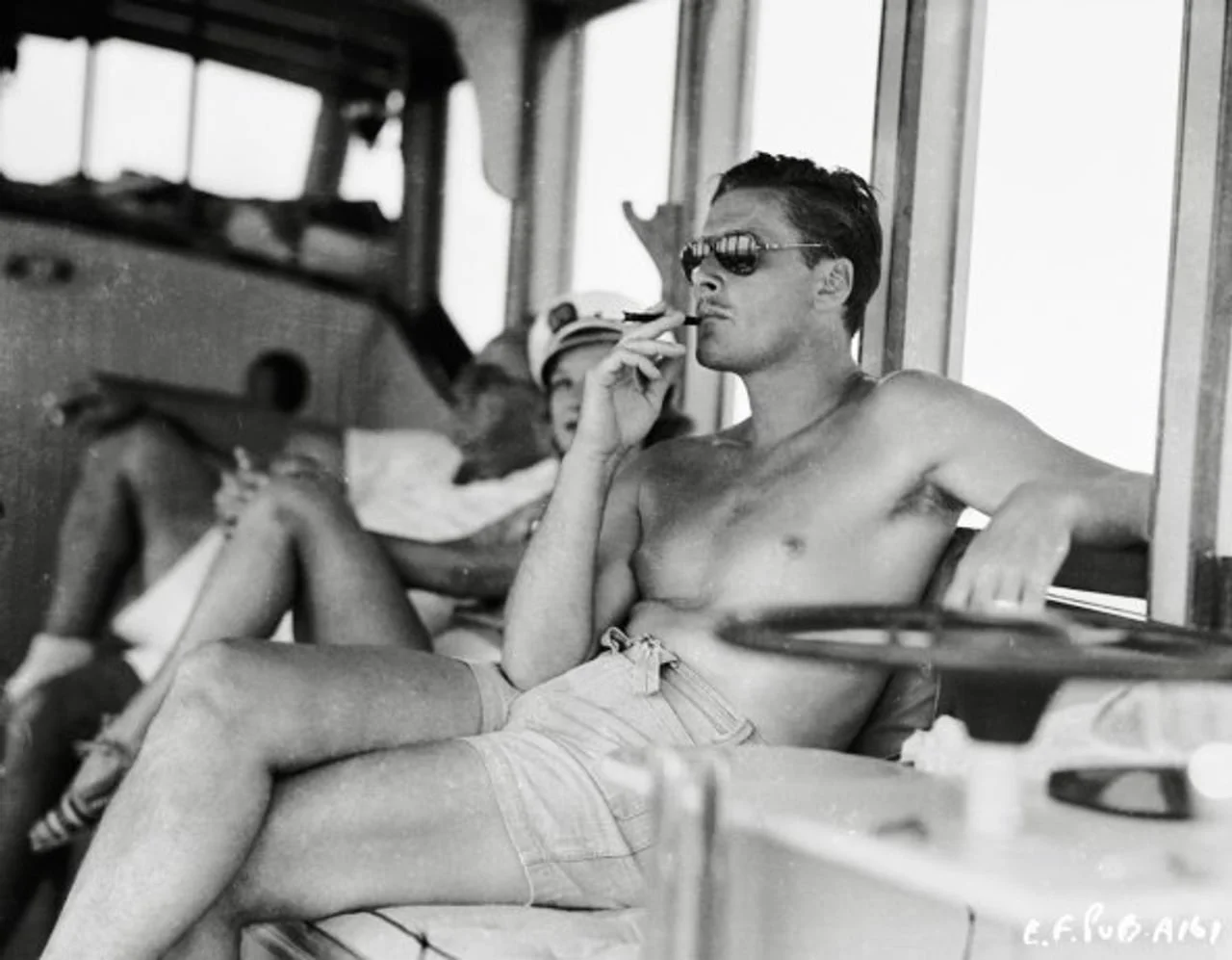 Errol Flynn bez majice s narančastim naočalama na palubi broda