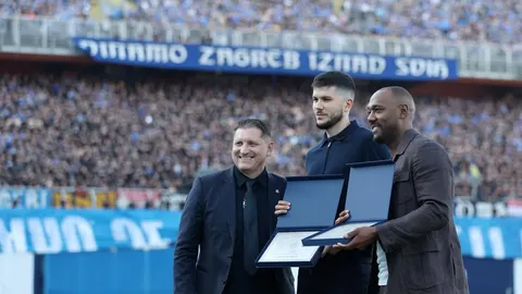 Dino Perić stoji između dvojice muškaraca i drži otvorenu plavu mapu