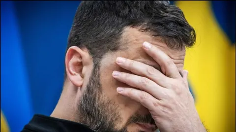 Krupni plan Volodimira Zelenskog koji drži ruku na čelu