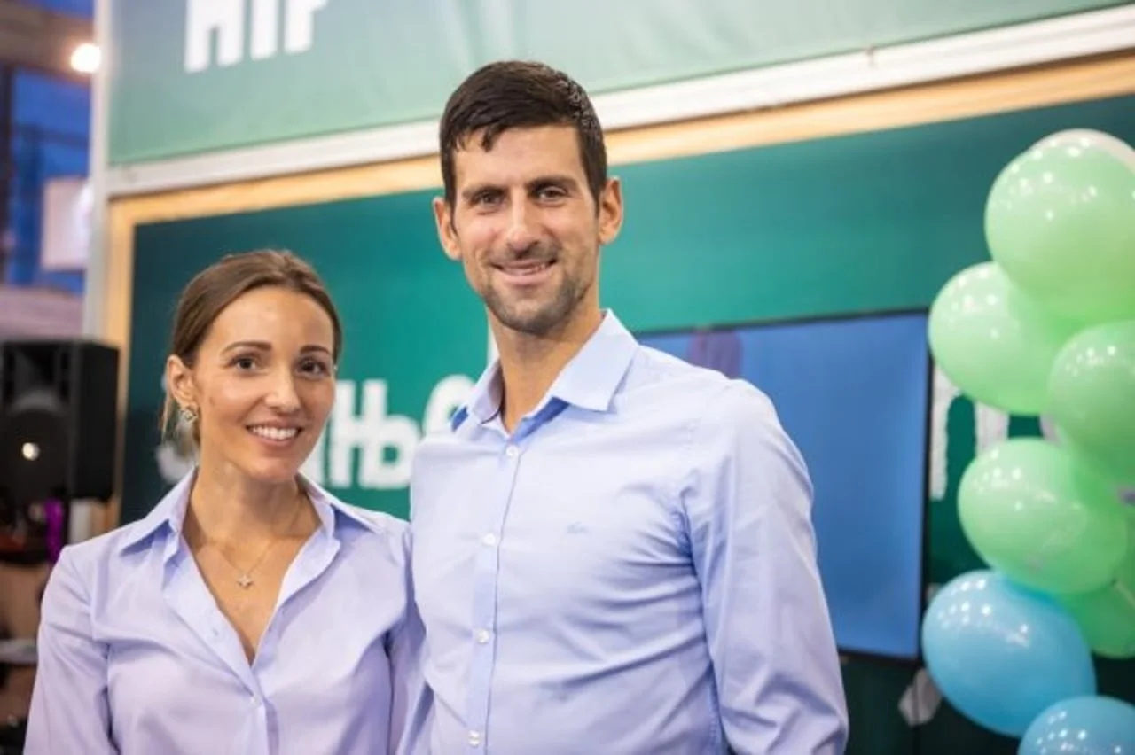 Novak i Jelena Đoković u svijetlim košuljama ispred zelenog pozadnjeg plana