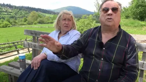 Halid Bešlić i njegova supruga Sejda sjede na drvenoj klupi u prirodi