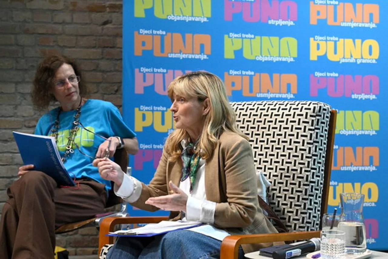 Sanja Doležal govori na panelu ispred plavog zida s natpisima