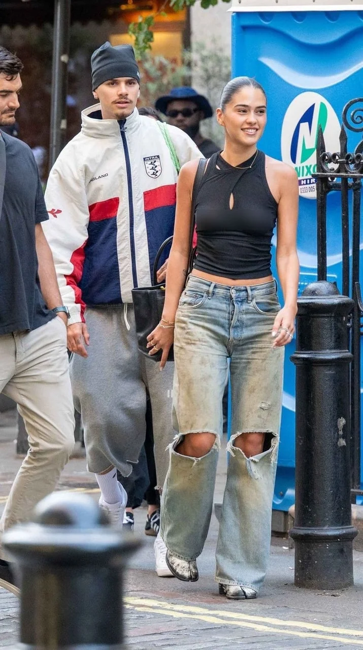 Young woman in black top and ripped jeans walking with a man