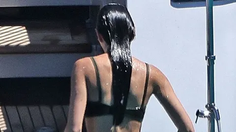 Woman with long dark hair in a black bikini from behind