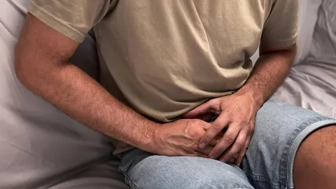 Muškarac u majici i trapericama koji drži ruke na području zdjelice