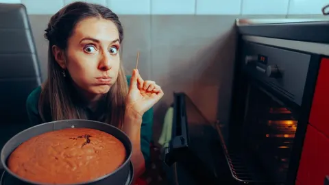 Žena drži čačkalicu pored pečenog biskvita iz rerne