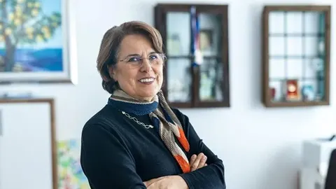 Portret nasmijane žene s naočalama i šalom, stoji s prekriženim rukama