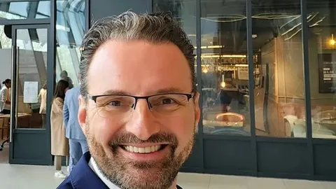 Portret nasmijanog muškarca s naočalama i urednom bradom