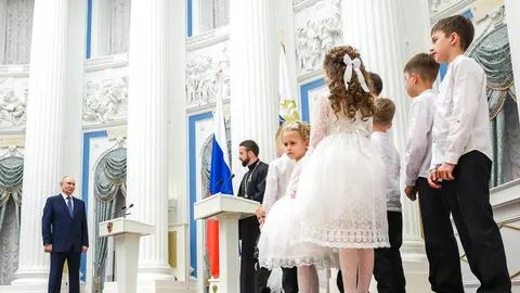 Vladimir Putin stoji pored grupe djece u svečanoj bijeloj odjeći u palači