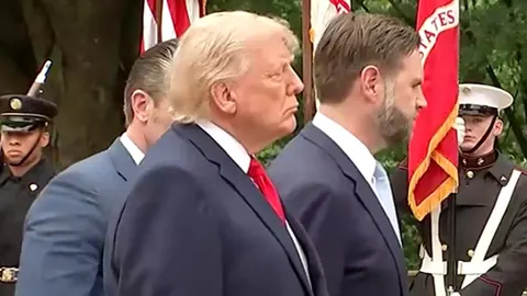 Donald Trump u tamnom odelu i crvenoj kravati stoji u profilu