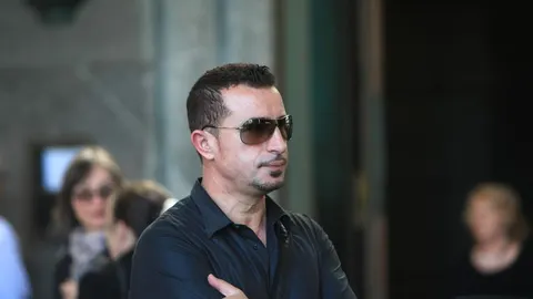Muškarac srednjih godina u crnoj košulji i sunčanim naočalama