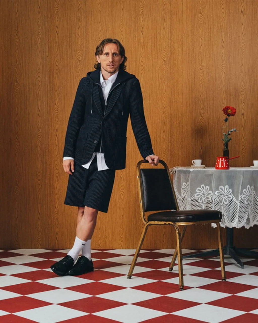Luka Modrić stoji pored stolice u prostoriji s drvenim zidovima