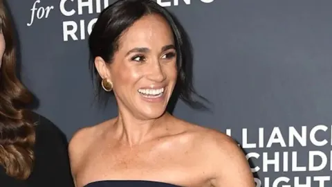 Nasmiješena Meghan Markle u tamnomodanom kombinezonu na događaju u Beverly Hillsu