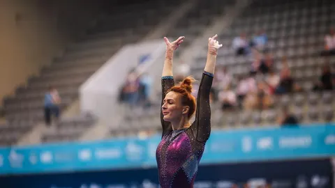 Gimnastičarka Tijana Korent u blještavom dresu s podignutim rukama u dvorani