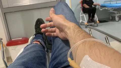 Ruka pacijenta s infuzijskom kanilom i traka preko ozljede na trapericama