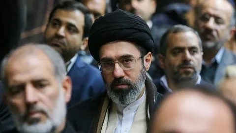 Modžtaba Khamenei s crnom turbanom i naočalama u okruženju muškaraca