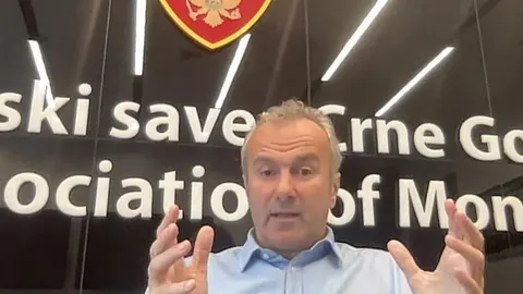 Dejan Savićević u plavoj košulji gestikulira rukama ispred logotipa saveza