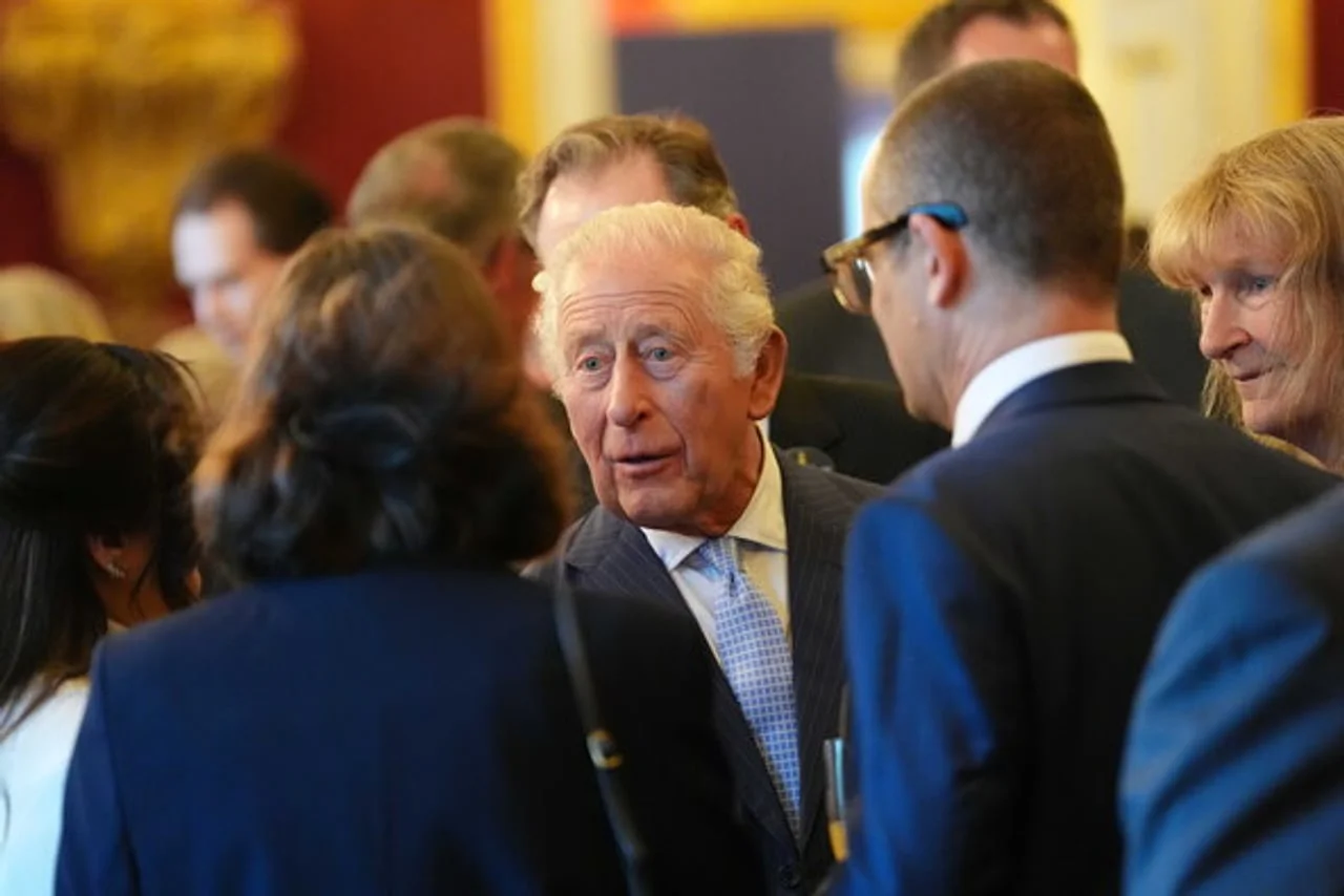 Kralj Charles III u tamnom odelu razgovara s gostima na događaju
