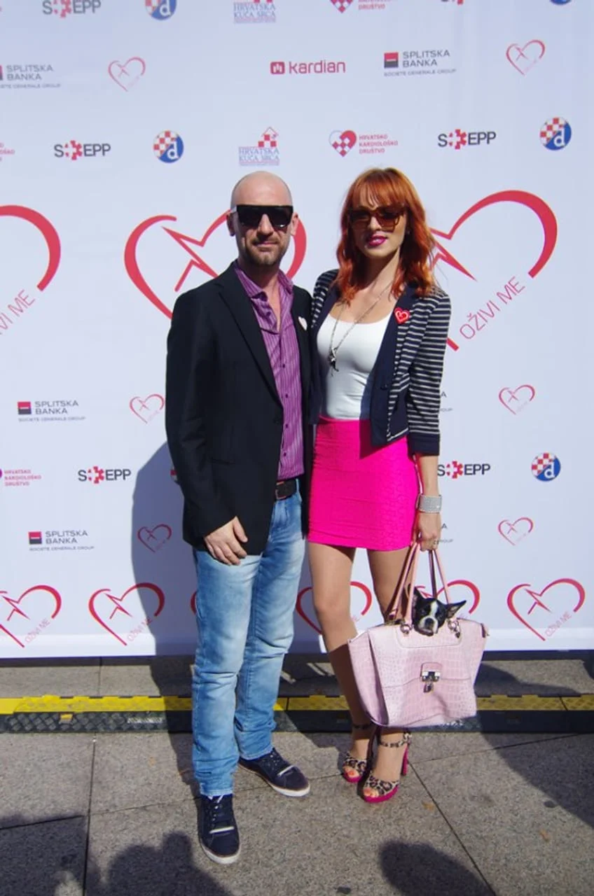 Muškarac i žena s crvenom kosom ispred promotivnog zida