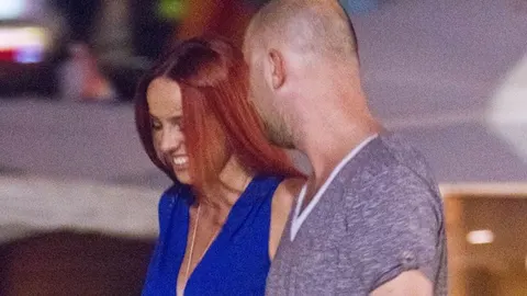 Nasmijana žena u plavoj haljini i muškarac u sivoj majici