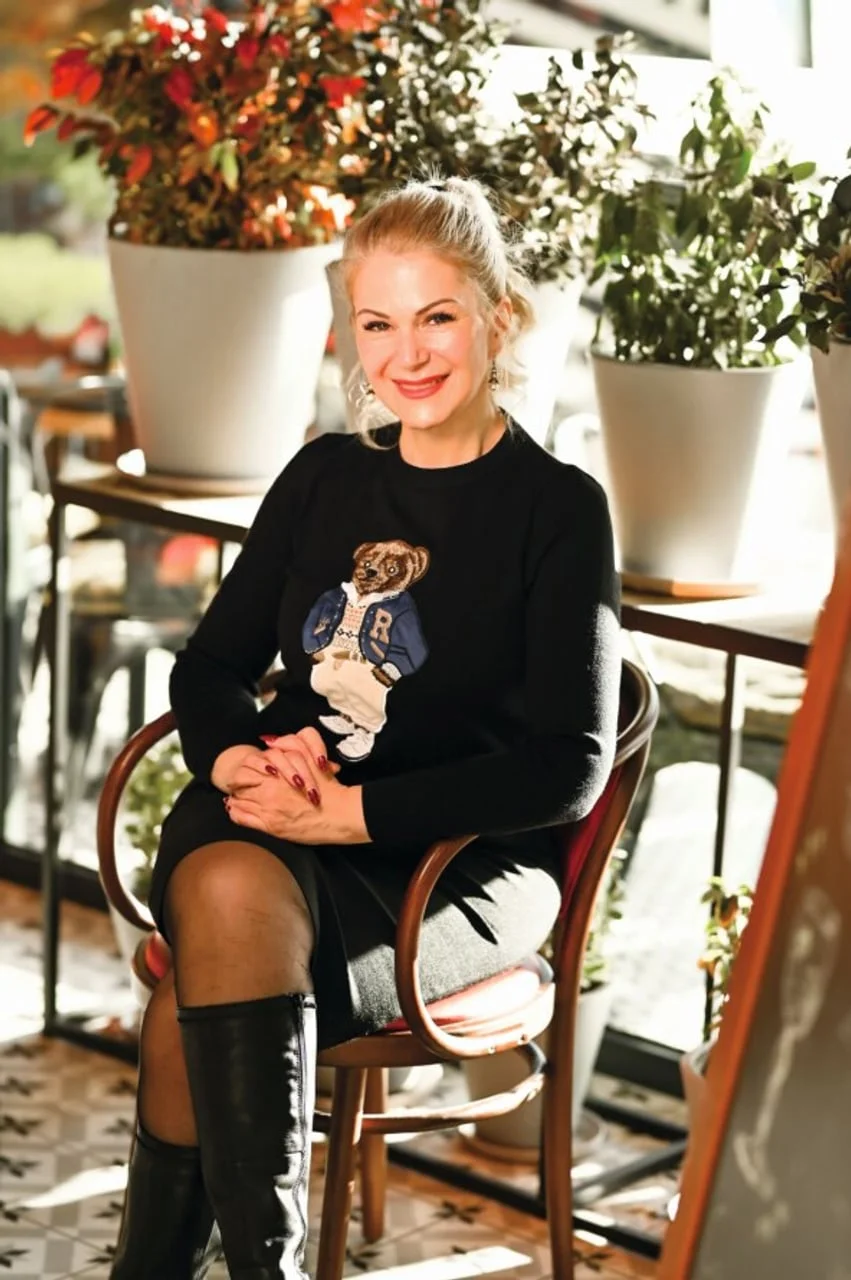 Osmijana plavokosa žena u crnom džemperu s motivom medvjeda