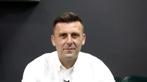 Portret muškarca srednjih godina u bijeloj košulji pred tamnim zidom
