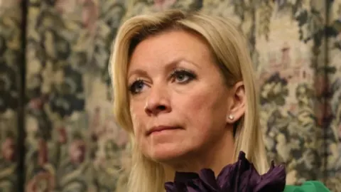 Portret plavuše u ozbiljnom izrazu lica ispred ukrasnih zapoja
