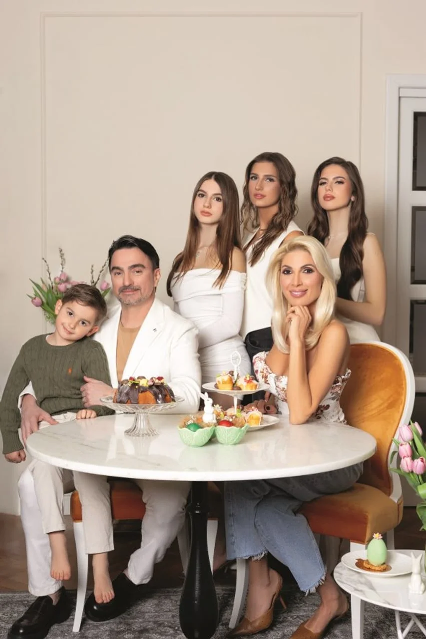 Obitelj Jole i Ane sjedi za stolom s kolačima u svijetlom interijeru