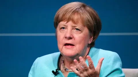 Portret Angele Merkel u svijetlo plavom saku koji gestikulira rukom