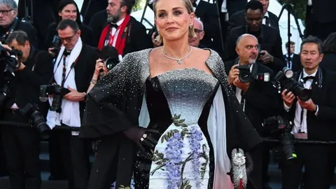Šeron Stoun u elegantnoj crno-bijeloj haljini s cvjetnim uzorkom na crvenom tepihu