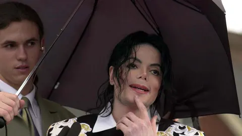 Michael Jackson pod crnim kišobranom u pratnji tjelohranitelja