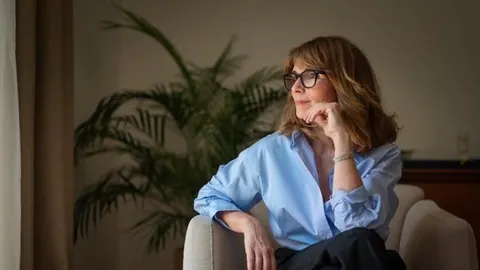 Srednje starija žena s naočalama razmišlja u udobnom dnevnom boravku