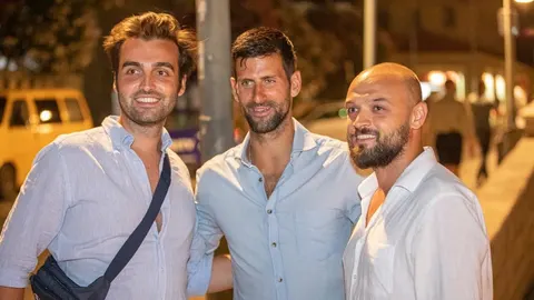 Novak Đoković u sredini s dvojicom muškaraca u svijetlim košuljama
