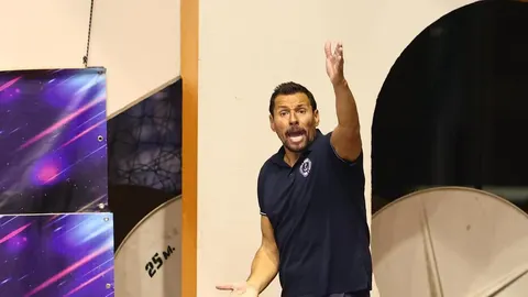 Muškarac u tamnoplavoj polo majici s podignutom rukom i otvorenim ustima