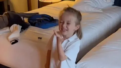 Mali dječak u bijeloj majici nasmijan u sobi
