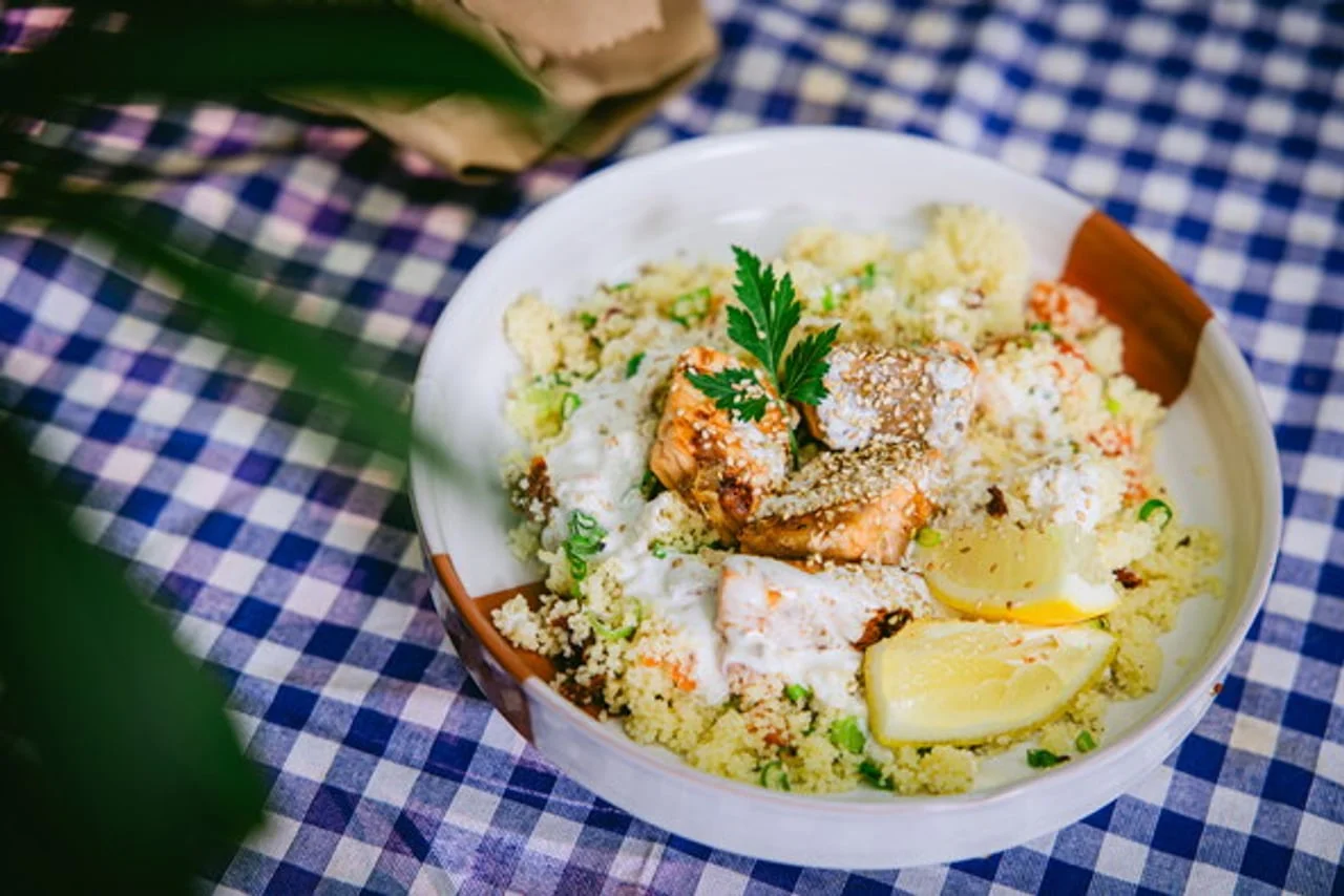 Bowl s kuskusom, pečenom ribom, bijelim umakom i limunom