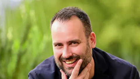 Portret nasmijanog muškarca s bradom u tamnom saku
