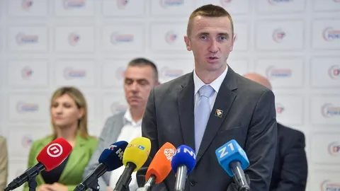 Stjepa Bartulica u sivoj pogodnom odjeću govori pred mikrofonima novinara