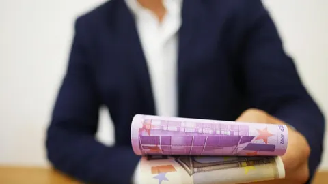 Rukom držani svitci novčanica eura u prvom planu