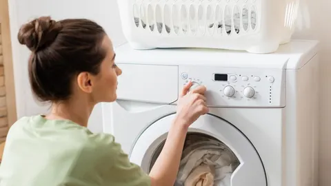 Žena namješta program pranja na bijeloj perilici rublja