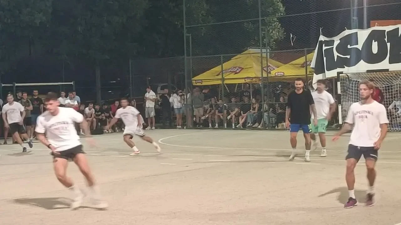 Nogometnaši u bijelim majicama igraju nogomet na malom terenu