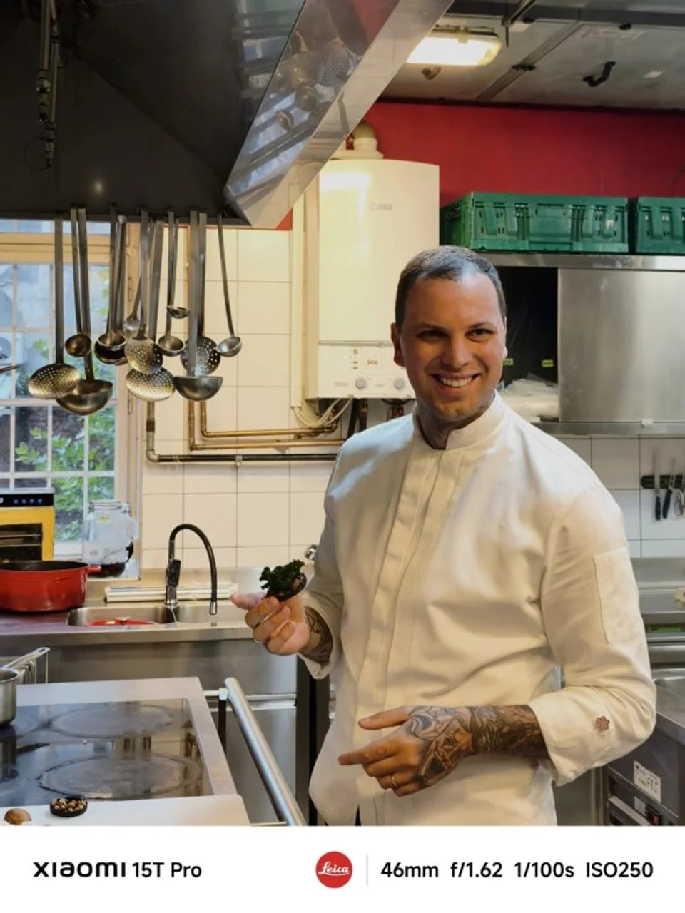 Chef u bijeloj kuhinjskoj jakni stoji u profesionalnoj kuhinji