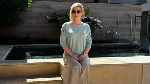Kolinda Grabar-Kitarović u svijetlim hljabima sjedi pored bazena